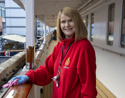 Housekeeper polishes the teak handrails on the Shelter Deck.